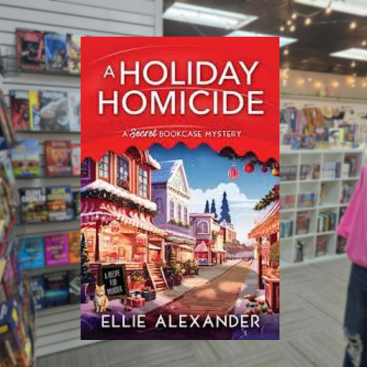 A Holiday Homicide by Ellie Alexander Christmas cozy mystery paperback cover featuring a charming snow-covered town decorated with Christmas lights, festive storefronts, and a clock tower.