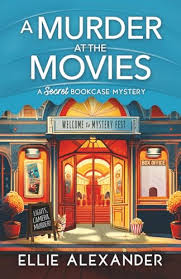 A Murder at the Movies by Ellie Alexander cozy mystery paperback cover featuring a vintage movie theater with glowing lights, a red carpet entrance, movie posters, and a popcorn container.