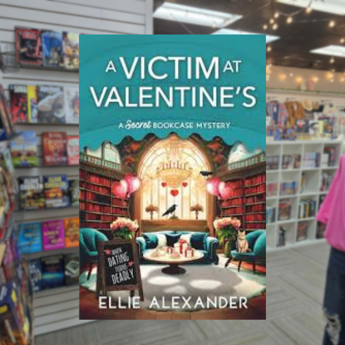 A Victim at Valentine's by Ellie Alexander cozy mystery book cover featuring a charming bookstore with tall bookshelves, pink heart-shaped decorations, cozy reading chairs, and a Valentine's Day display.