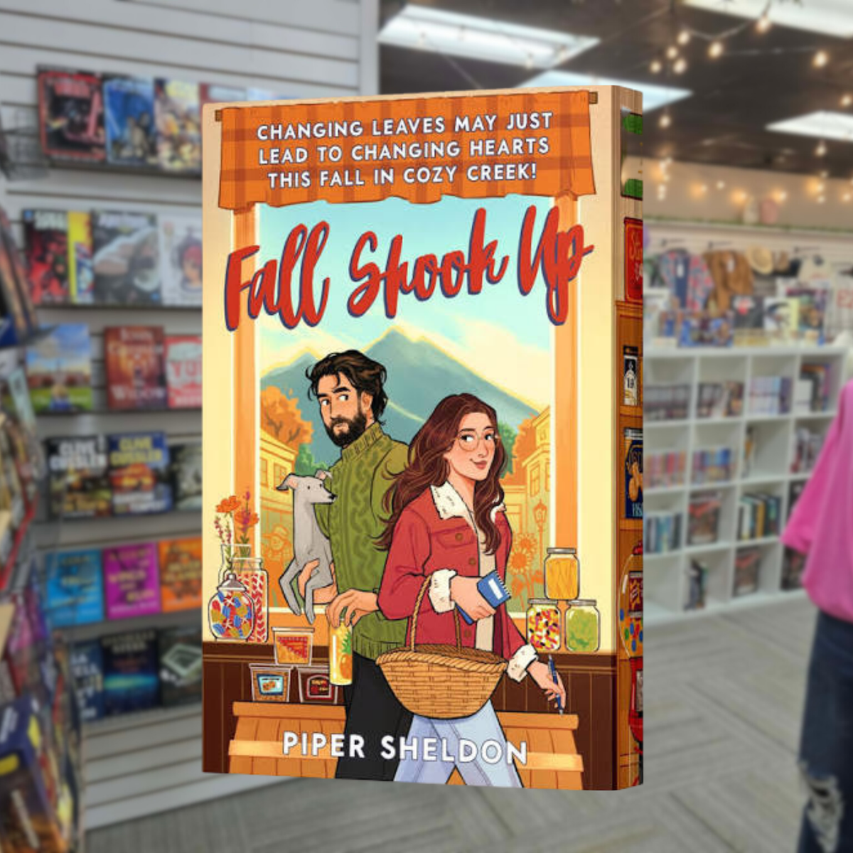Fall Shook Up by Piper Sheldon cozy autumn romance book cover featuring an illustrated couple in a small-town shop with a gray cat