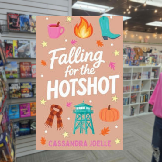 Falling for the Hotshot by Cassandra Joelle romance book cover featuring autumn leaves, cowboy boots, a coffee mug, scarf, pumpkin, flames, and a turquoise fire lookout tower.