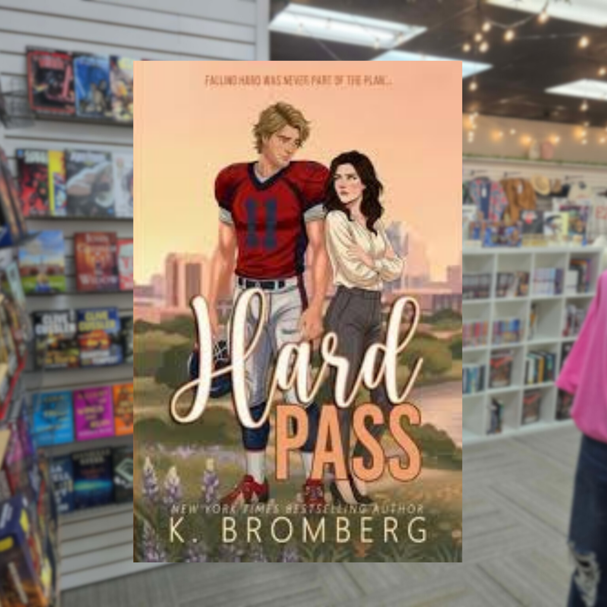 Hard Pass by K. Bromberg sports romance book cover featuring an illustrated blond football player in a red jersey standing beside a brunette woman against a city skyline.