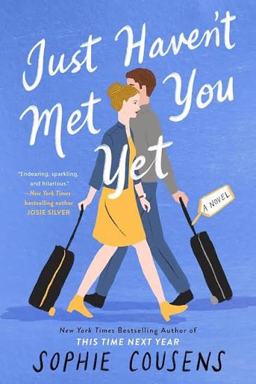 Just Haven't Met You Yet by Sophie Cousens paperback romantic comedy book cover featuring an illustrated couple walking with suitcases against a blue background