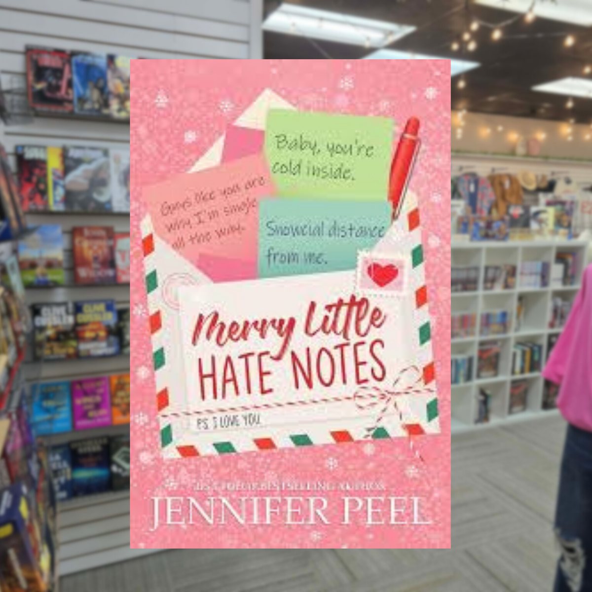 Merry Little Hate Notes by Jennifer Peel Christmas romance book cover featuring a pink snowy background, festive airmail envelope, colorful handwritten notes, and a red pencil.