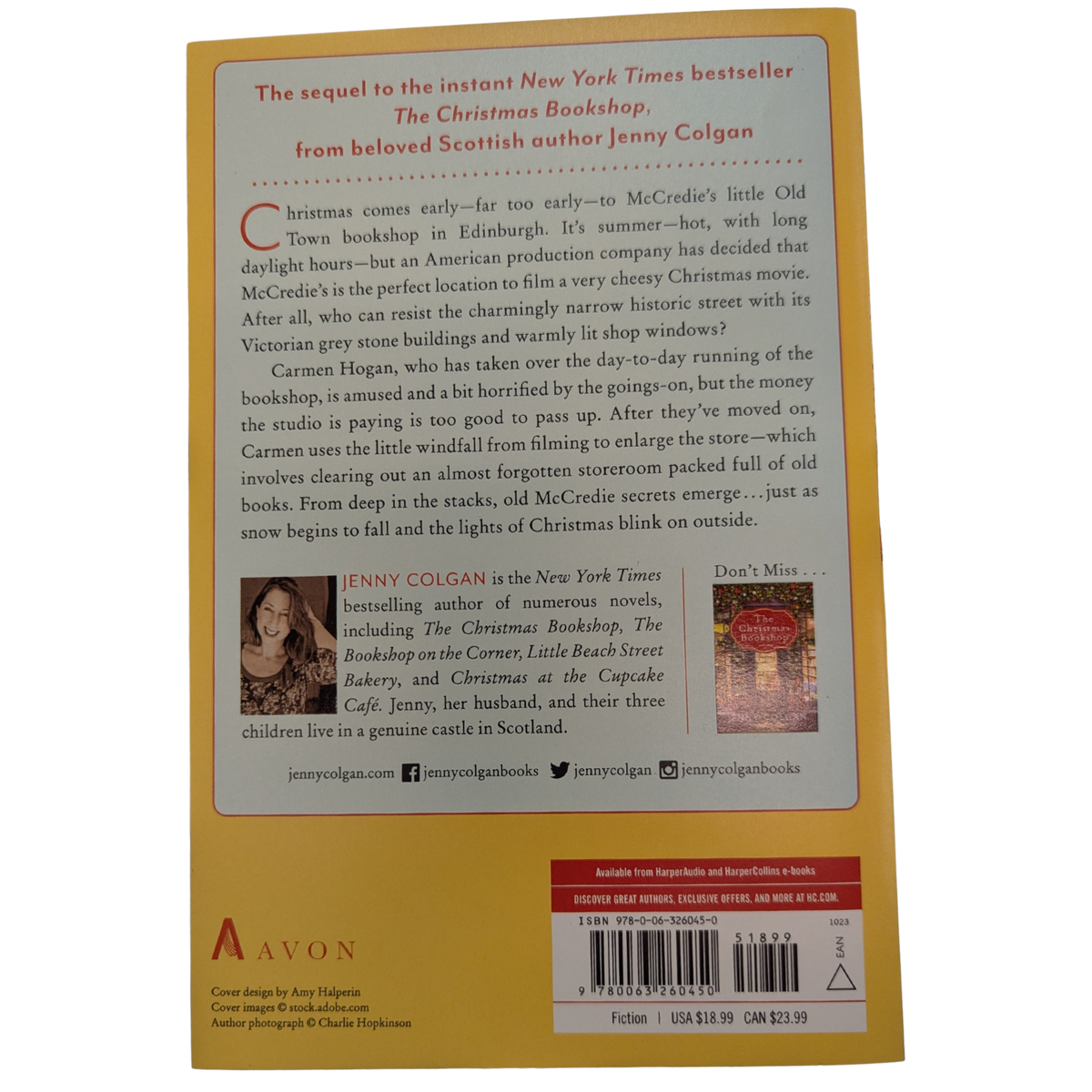 Midnight at the Christmas Bookshop by Jenny Colgan paperback cover featuring a festive red bookstore decorated with Christmas garlands, a colorful Christmas tree, wrapped presents, and snow