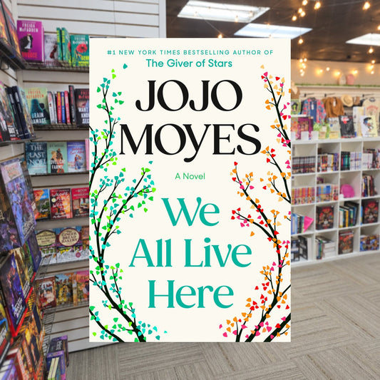 We All Live Here by Jojo Moyes — actual cover on The Perk bookstore background