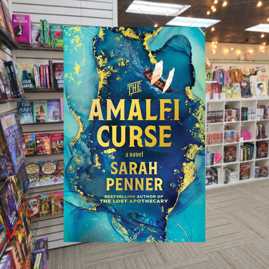 The Amalfi Curse by Sarah Penner — actual cover on The Perk bookstore background