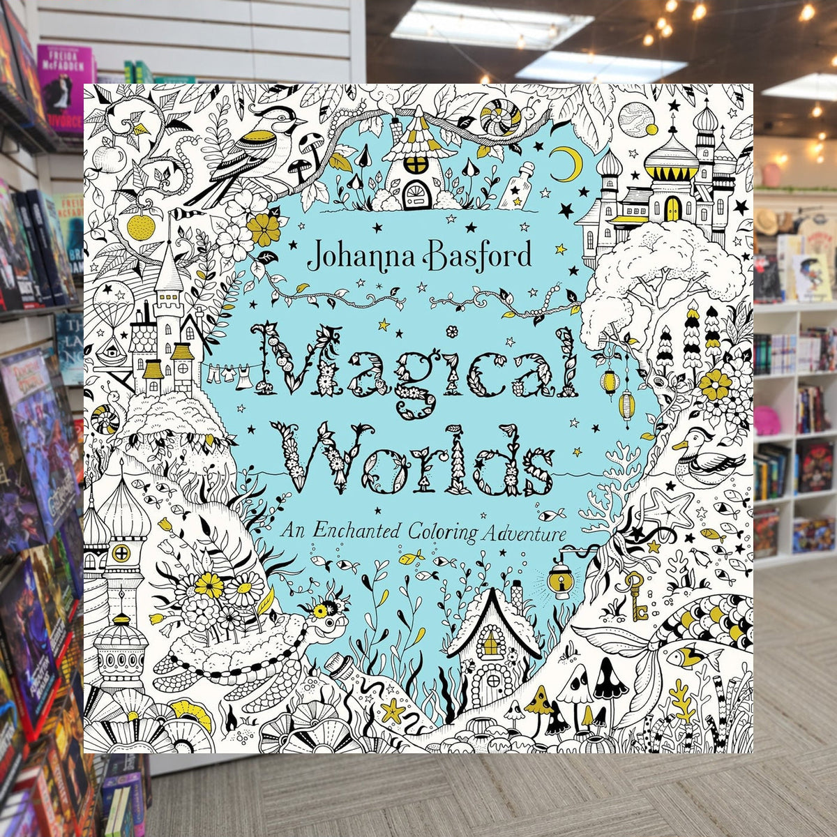 Magical Worlds: An Enchanted Coloring Adventure by Johanna Basford — actual cover on The Perk bookstore background
