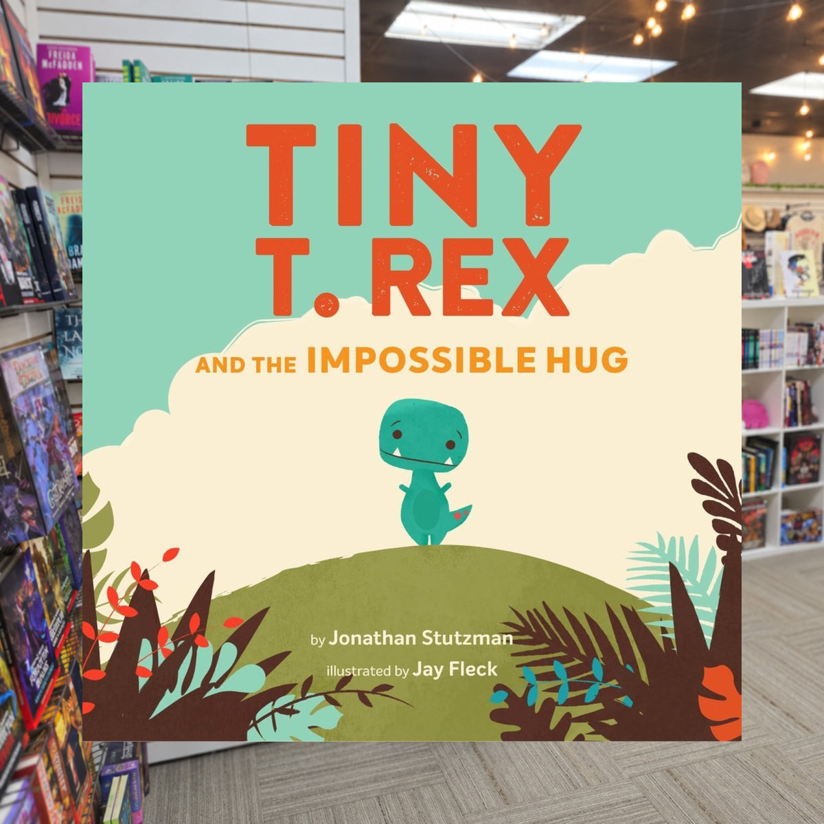 Tiny T. Rex and the Impossible Hug by Jonathan Stutzman — actual cover on The Perk bookstore background