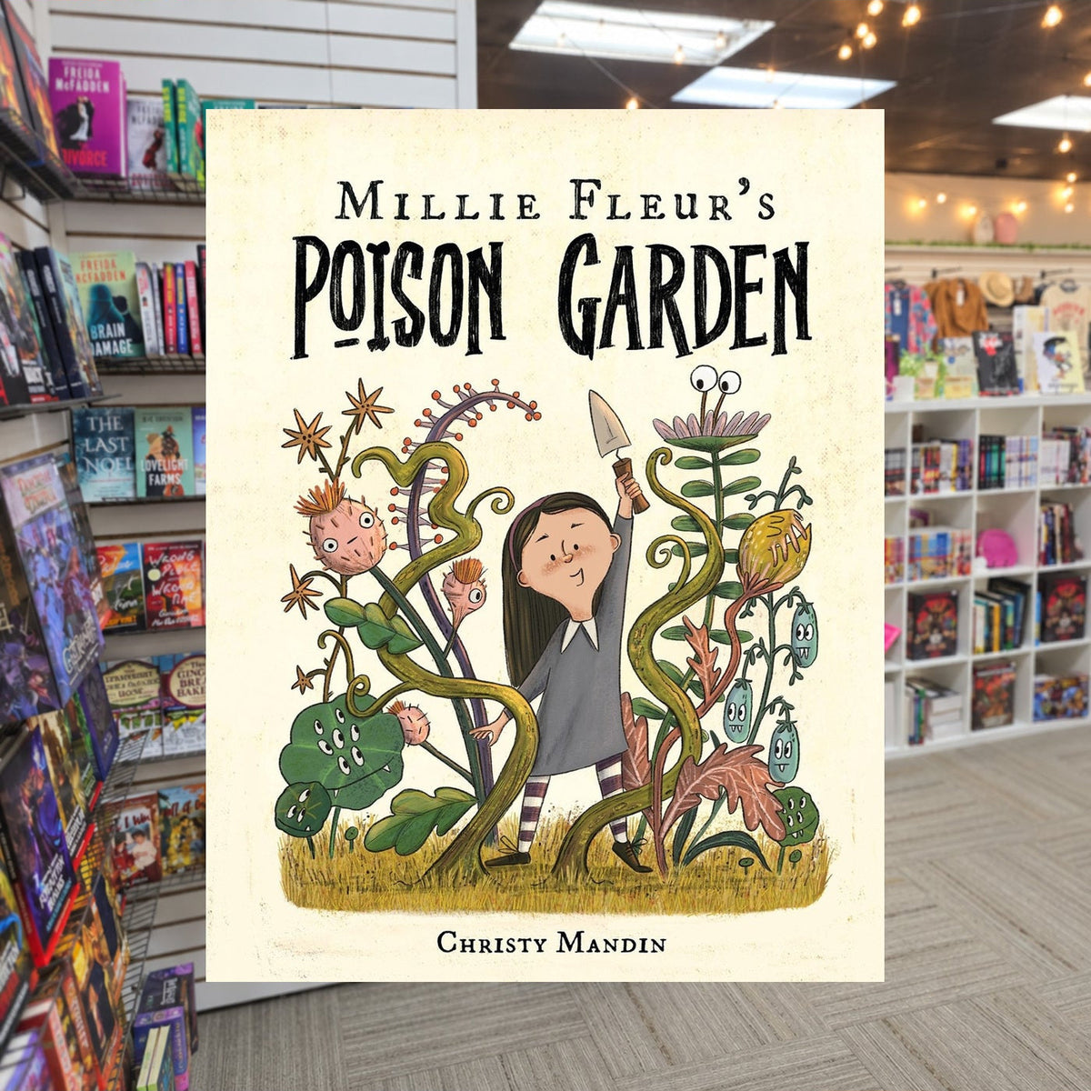 Millie Fleur's Poison Garden by Christy Mandin — actual cover on The Perk bookstore background