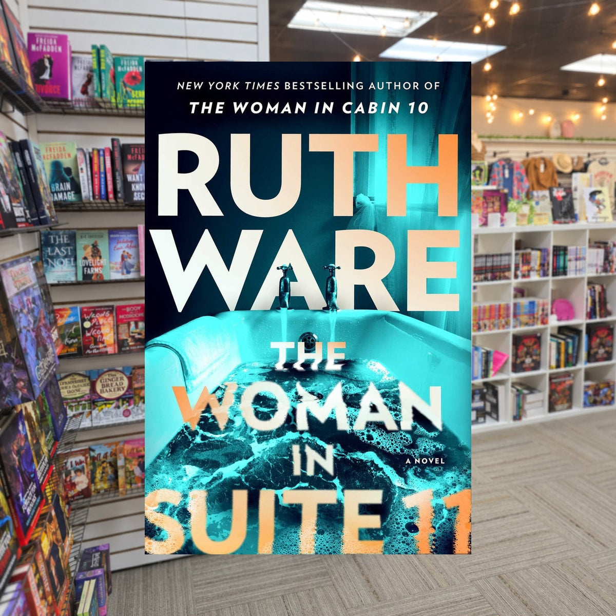 The Woman In Suite 11 by Ruth Ware — actual cover on The Perk bookstore background