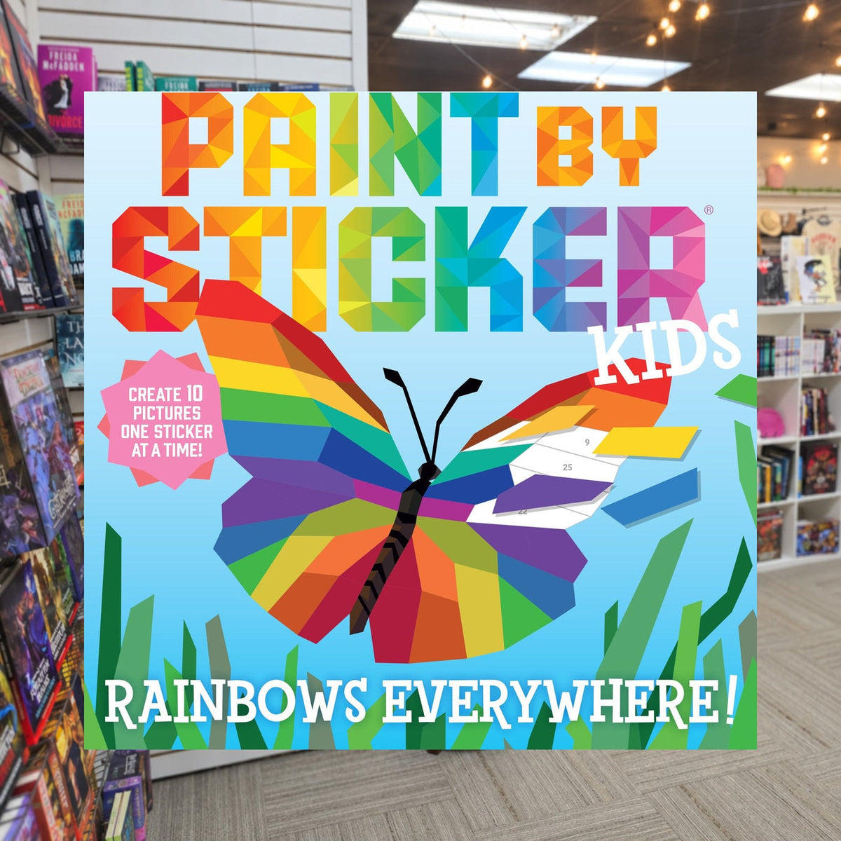 Paint by Sticker Kids: Rainbows Everywhere!: Create 10 Pictures One Sticker at a Time! by Workman Publishing — actual cover on The Perk bookstore background