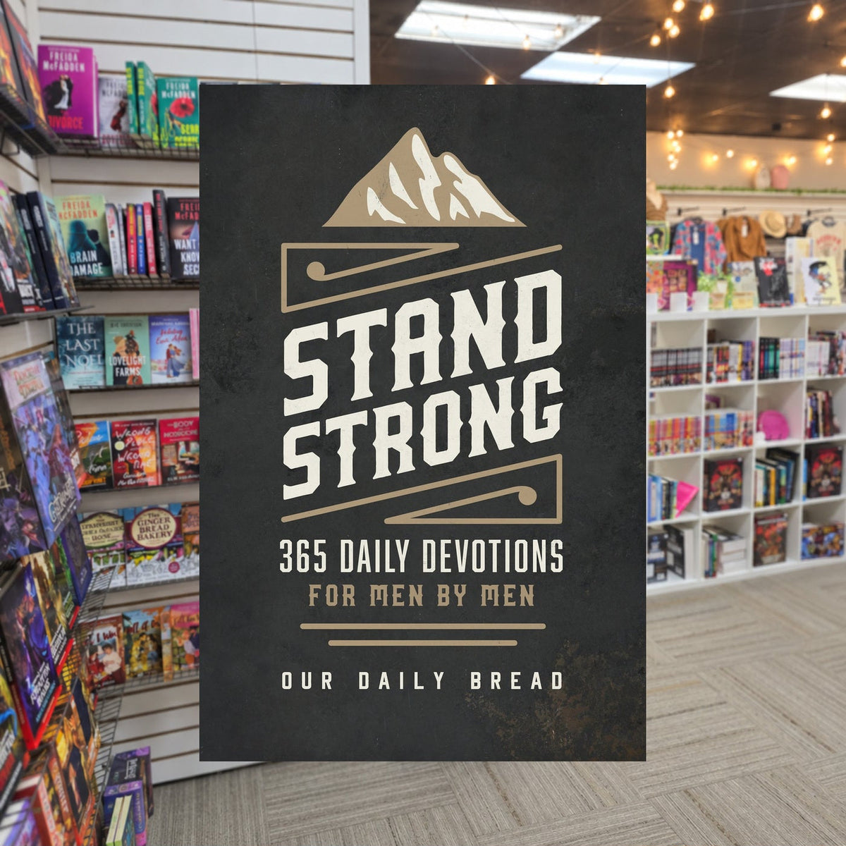 Stand Strong: 365 Devotions for Men by Men — actual cover on The Perk bookstore background