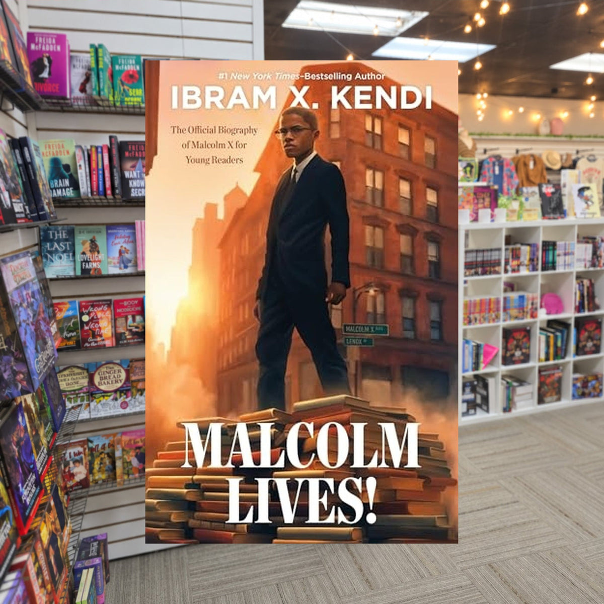 Malcolm Lives!: The Official Biography of Malcolm X for Young Readers by Ibram X. Kendi — actual cover on The Perk bookstore background