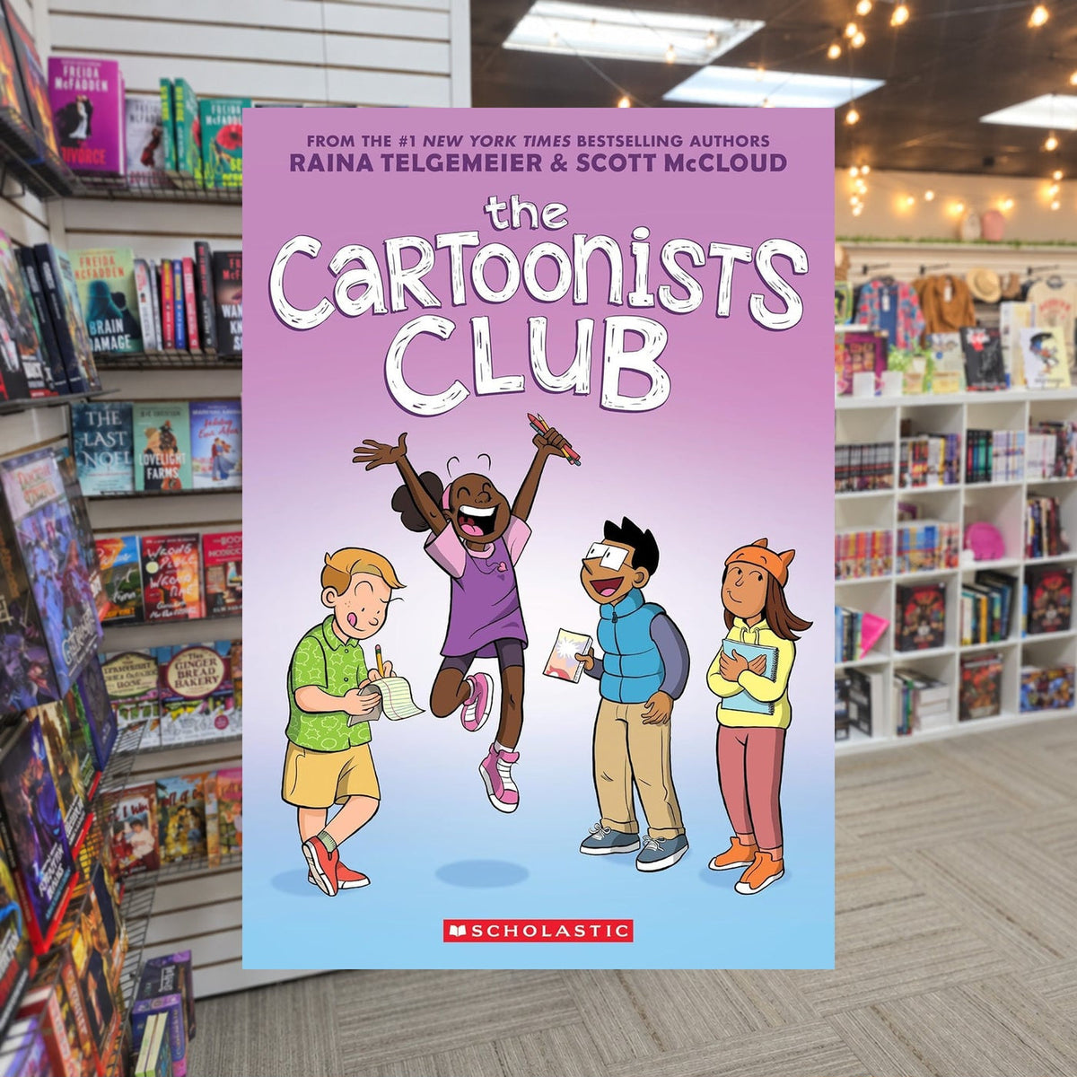 The Cartoonists Club by Raina Telgemeier — actual cover on The Perk bookstore background