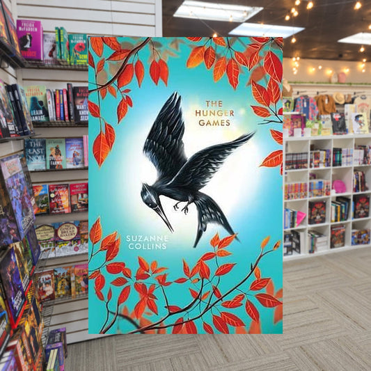 The Hunger Games by Suzanne Collins — actual cover on The Perk bookstore background