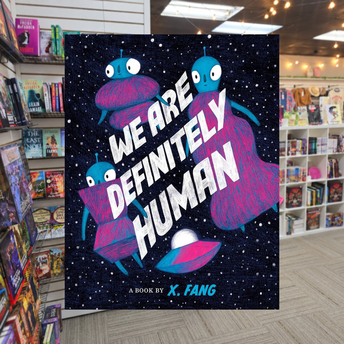 We Are Definitely Human by X. Fang — actual cover on The Perk bookstore background