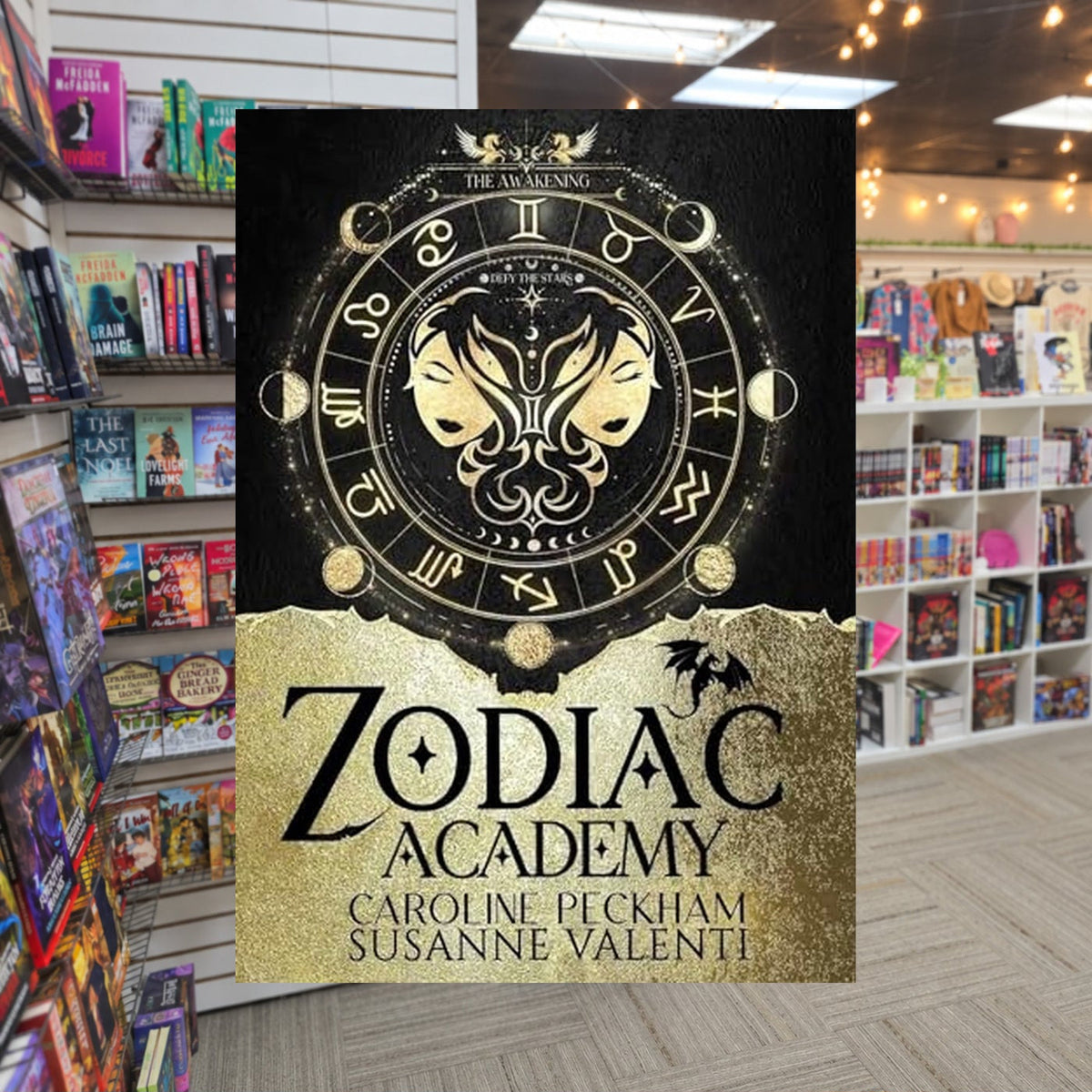 Zodiac Academy: The Awakening by Caroline Peckham and Susanne Valenti — actual cover on The Perk bookstore background