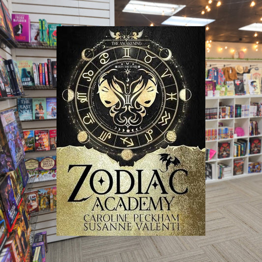 Zodiac Academy: The Awakening by Caroline Peckham and Susanne Valenti — actual cover on The Perk bookstore background