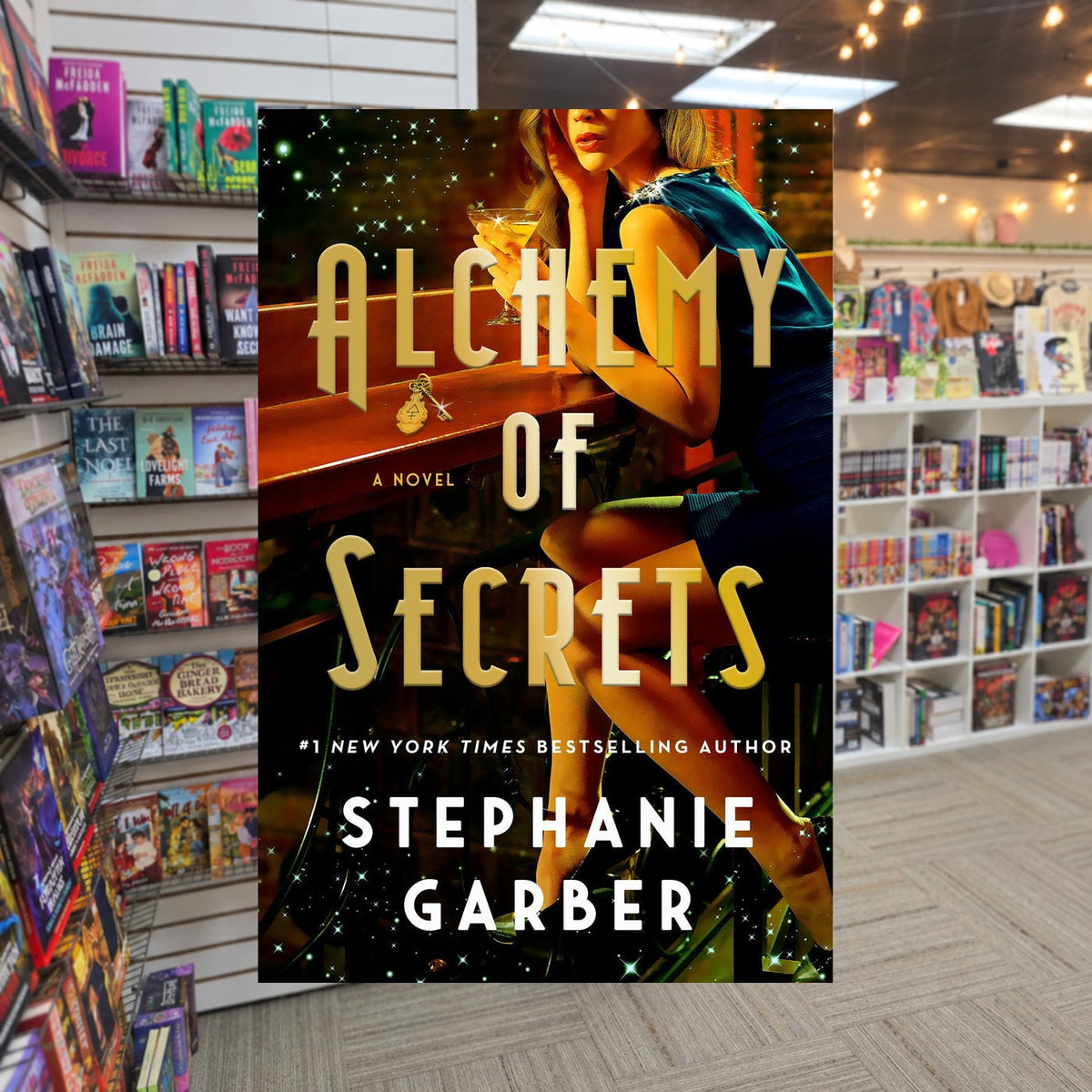 Alchemy of Secrets by Stephanie Garber — actual cover on The Perk bookstore background