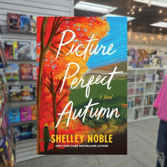 Picture Perfect Autumn by Shelley Noble paperback book cover featuring vibrant orange autumn leaves, a scenic countryside landscape and a colorful fall sky