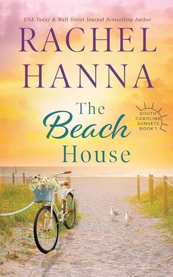The Beach House by Rachel Hanna paperback cover featuring a bicycle with a basket of flowers on a sandy path leading to the beach at sunset.