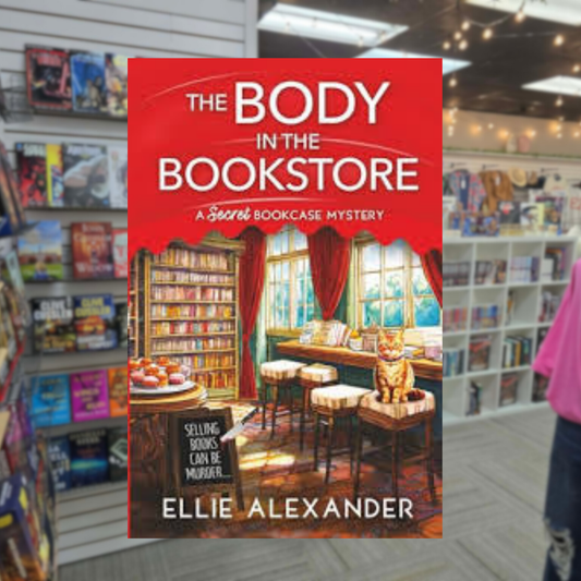 The Body in the Bookstore by Ellie Alexander cozy mystery paperback cover featuring a charming bookstore interior with bookshelves, a reading table, large windows, and red curtains.
