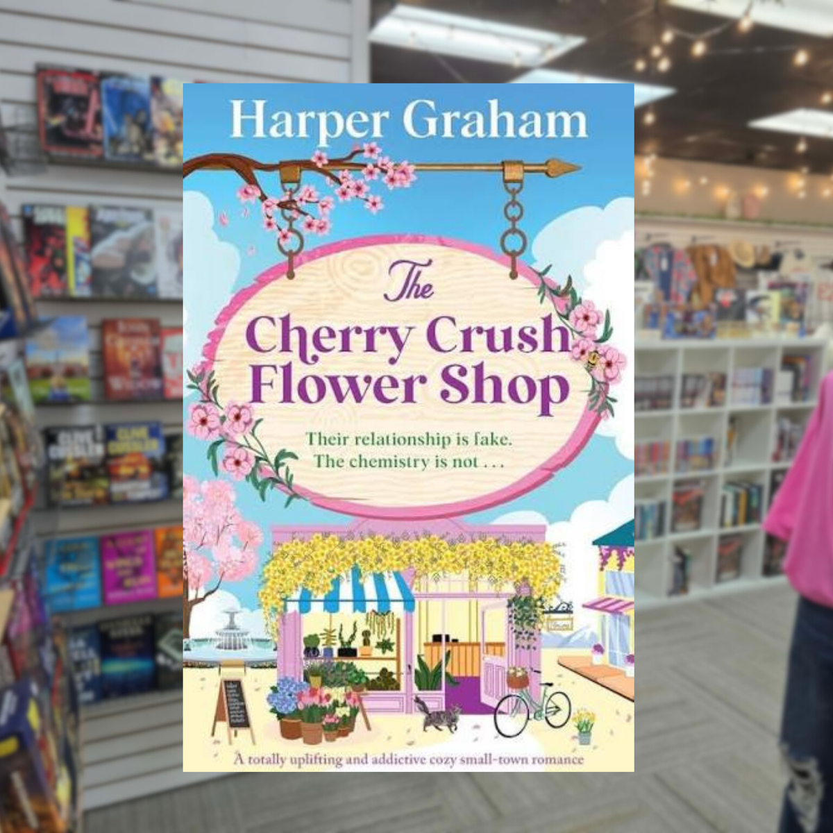 The Cherry Crush Flower Shop by Harper Graham romance book cover featuring a charming pink flower shop, blooming cherry blossoms, colorful flowers, and a bright blue sky.