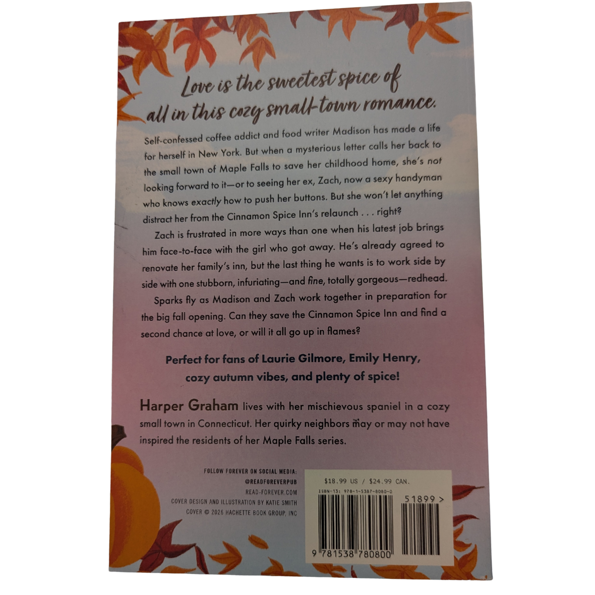 The Cinnamon Spice Inn by Harper Graham paperback cozy autumn romance book cover featuring a couple outside a charming inn surrounded by fall leaves and pumpkins