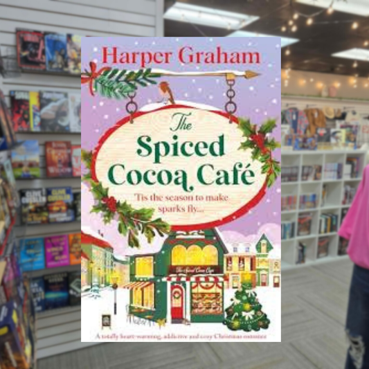 The Spiced Cocoa Café by Harper Graham Christmas romance book cover featuring a charming festive café, snow-covered buildings, Christmas greenery, colorful holiday decorations, and a snowy winter village.
