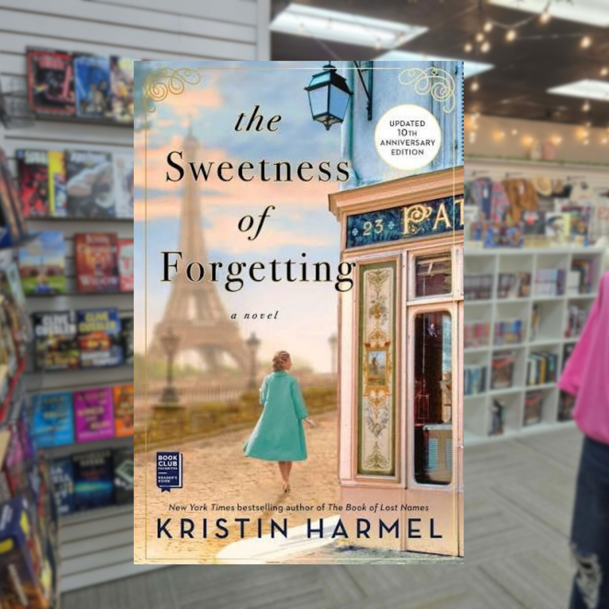 The Sweetness of Forgetting by Kristin Harmel Updated 10th Anniversary Edition paperback book cover featuring a woman in a turquoise coat walking toward the Eiffel Tower in Paris